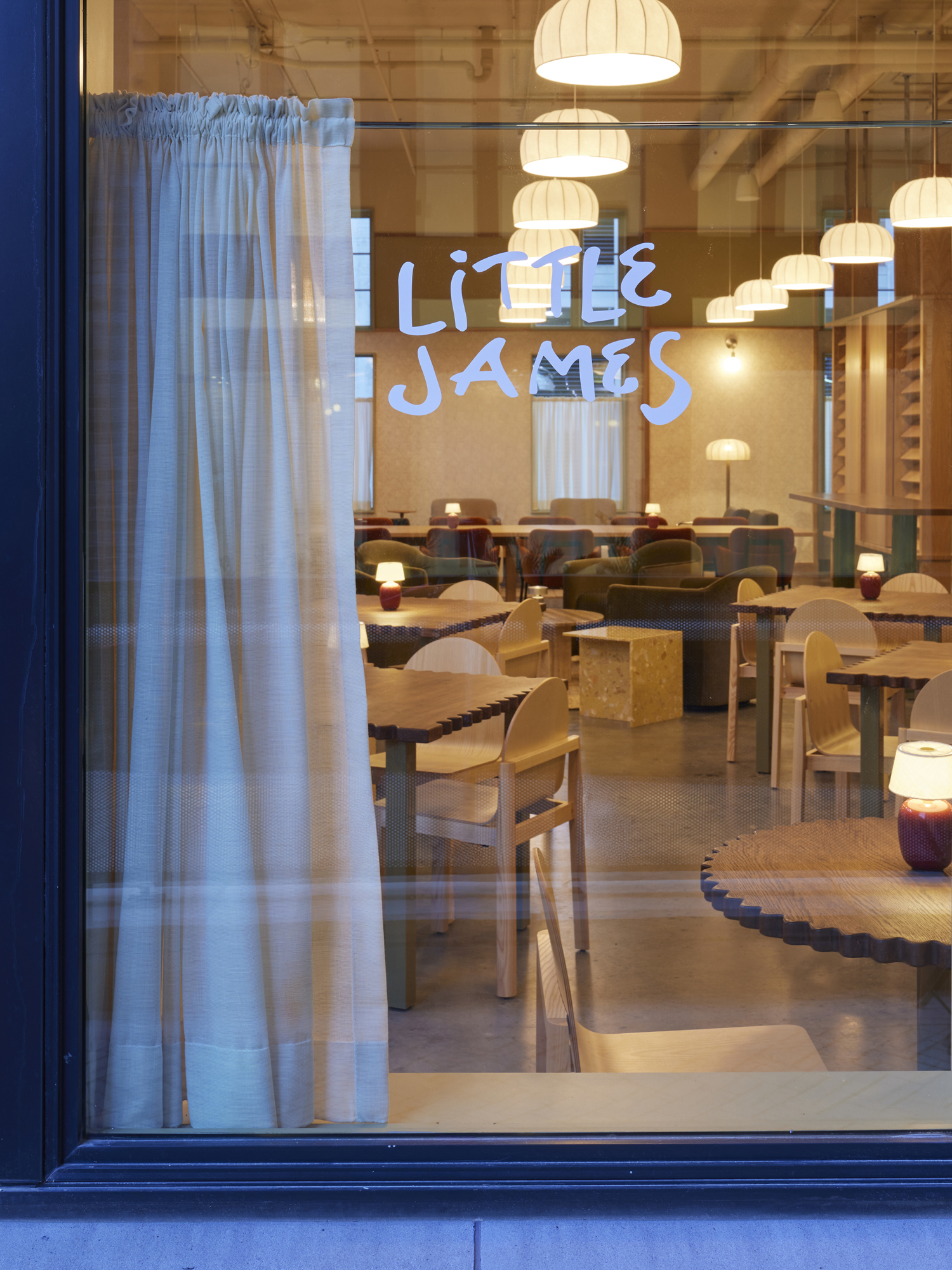 Little James cafe and bar interior at The Ann Savannah, warmly lit with wooden tables and pendant lights