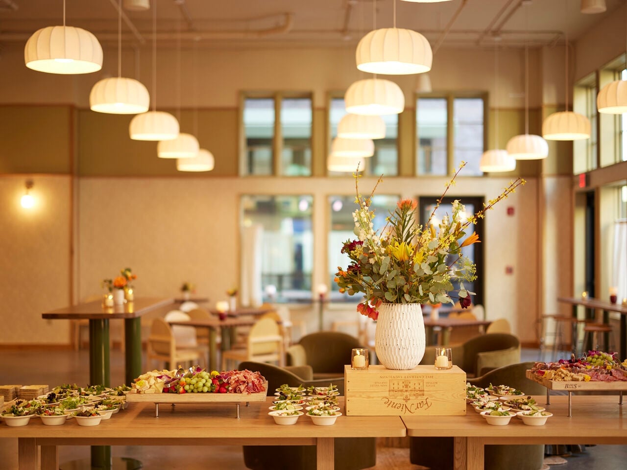 Buffet table in a Little James Restaurant with a tall white vase of colorful flowers and bowls of hors d'oeuvres.