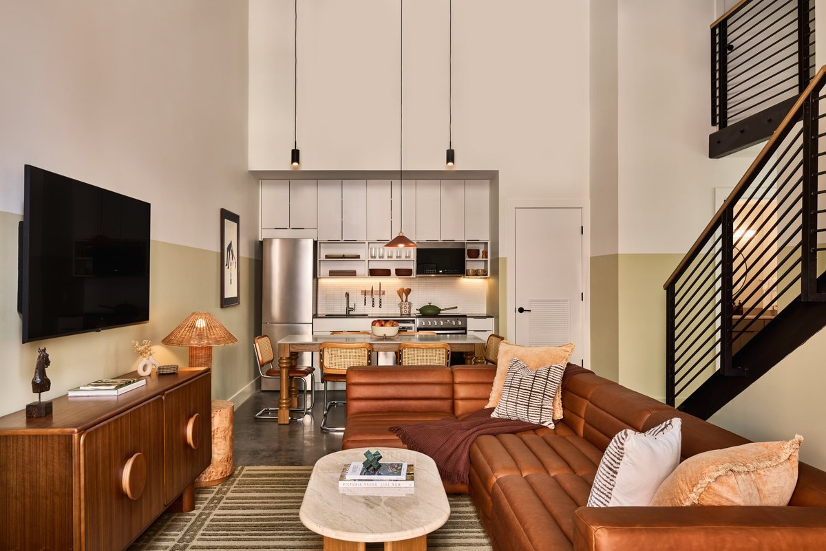 Three-bedroom loft with double-height ceilings, cognac leather sofa and staircase