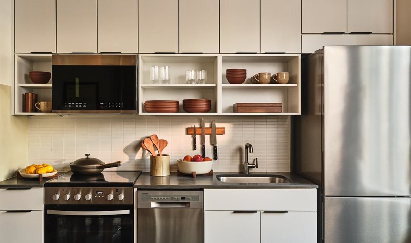 Suite kitchen wall with open shelving, dark stone counters and an induction hob