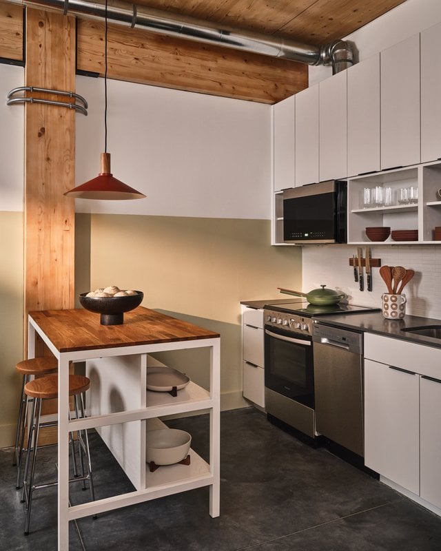 Loft suite kitchen with exposed wood beams, butcher block island and chrome bar stools